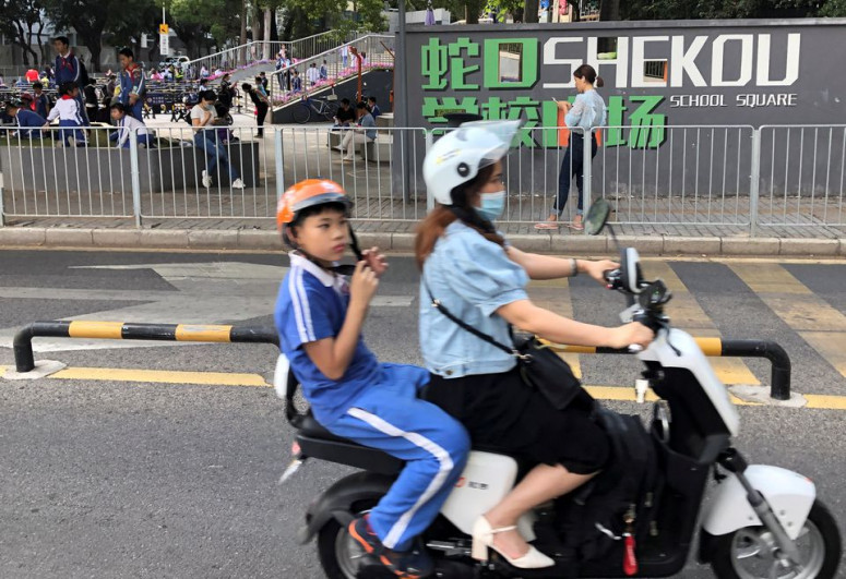A woman and a child ride away from a school in Shekou area of Shenzhen, Guangdong province, China April 20, 2021