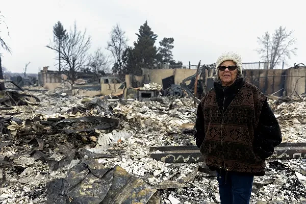 Linda Jackson stands in front of the remains of her two-story home, which was consumed during the Marshall Fire in Louisville, Colorado, 31 December 2021.