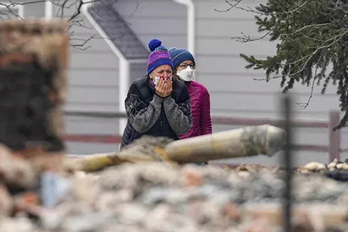 A woman cries as she sees the smouldering ruins of a home destroyed by the Marshall Wildfire in Louisville, Colorado, Friday, 31 December 2021.